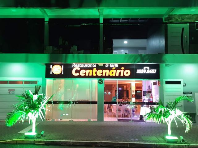 Fachada do Restaurante & Grill Centenário à noite, com iluminação verde.