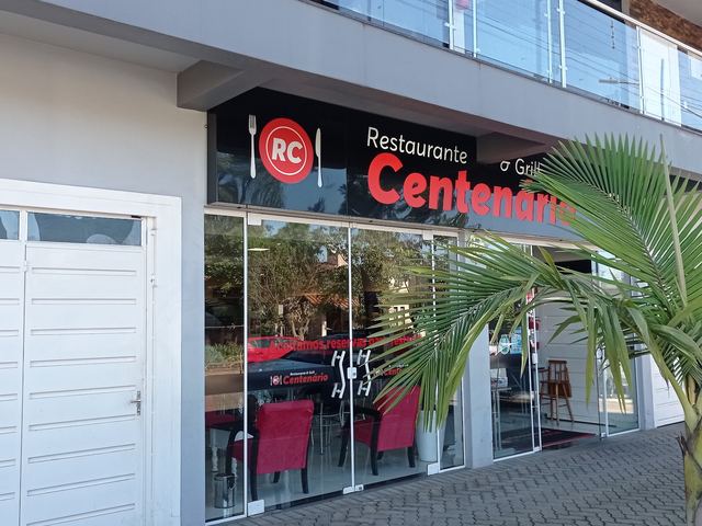 Fachada do Restaurante & Grill Centenário de dia, com as mesas visíveis pela vitrine.